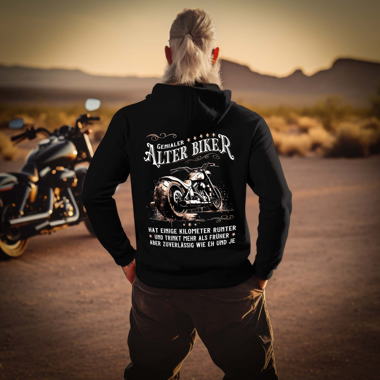 Ein Biker mit einem Hoodie für Motorradfahrer von Wingbikers mit dem Aufdruck, Alter Biker - Einige Kilometer runter, trinkt mehr - aber zuverlässig wie eh und je - mit Back Print, in schwarz.