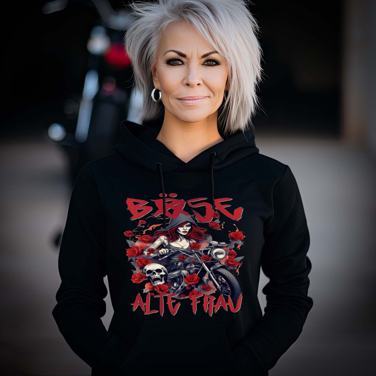 Eine Frau mit einem Hoodie für Motorradfahrerinnen von Wingbikers mit dem Aufdruck, Böse Alte Frau, in schwarz.