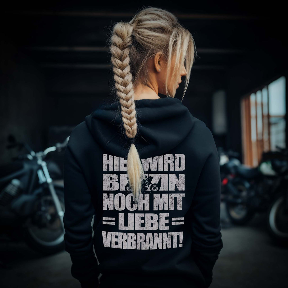Eine Motorradfahrerin mit einem Hoodie von Wingbikers mit dem Aufdruck, Hier wird Benzin noch mit Liebe verbrannt - mit Back Print, in schwarz.