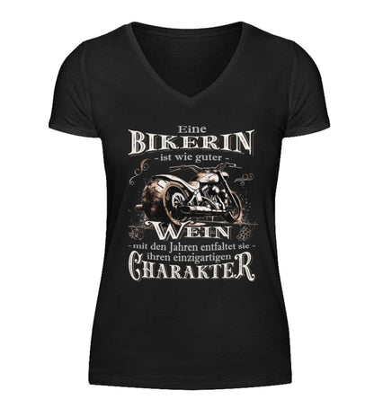 Ein Bikerin T-Shirt mit V-Ausschnitt für Motorradfahrerinnen von Wingbikers mit dem Aufdruck, Eine Bikerin ist wie guter Wein - mit den Jahren entfaltet sie ihren einzigartigen Charakter - in schwarz.