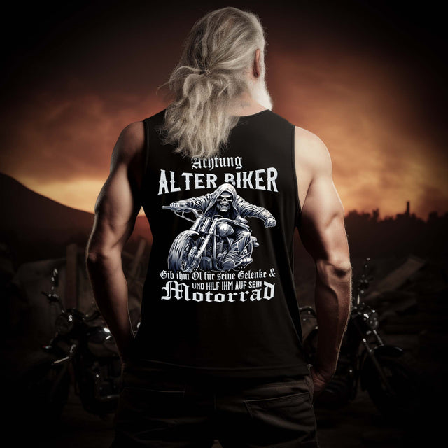 Ein Biker mit einem Tanktop für Motorradfahrer von Wingbikers mit dem Aufdruck, Achtung alter Biker - Gib ihm Öl und hilf ihm auf sein Motorrad - mit Back Print, in schwarz.