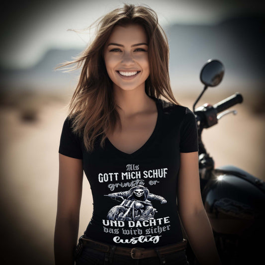 Eine Bikerin mit einem  T-Shirt mit V-Ausschnitt für Motorradfahrerinnen von Wingbikers mit dem Aufdruck, Als Gott mich schuf grinste er und dachte, das wird sicher lustig - in schwarz.