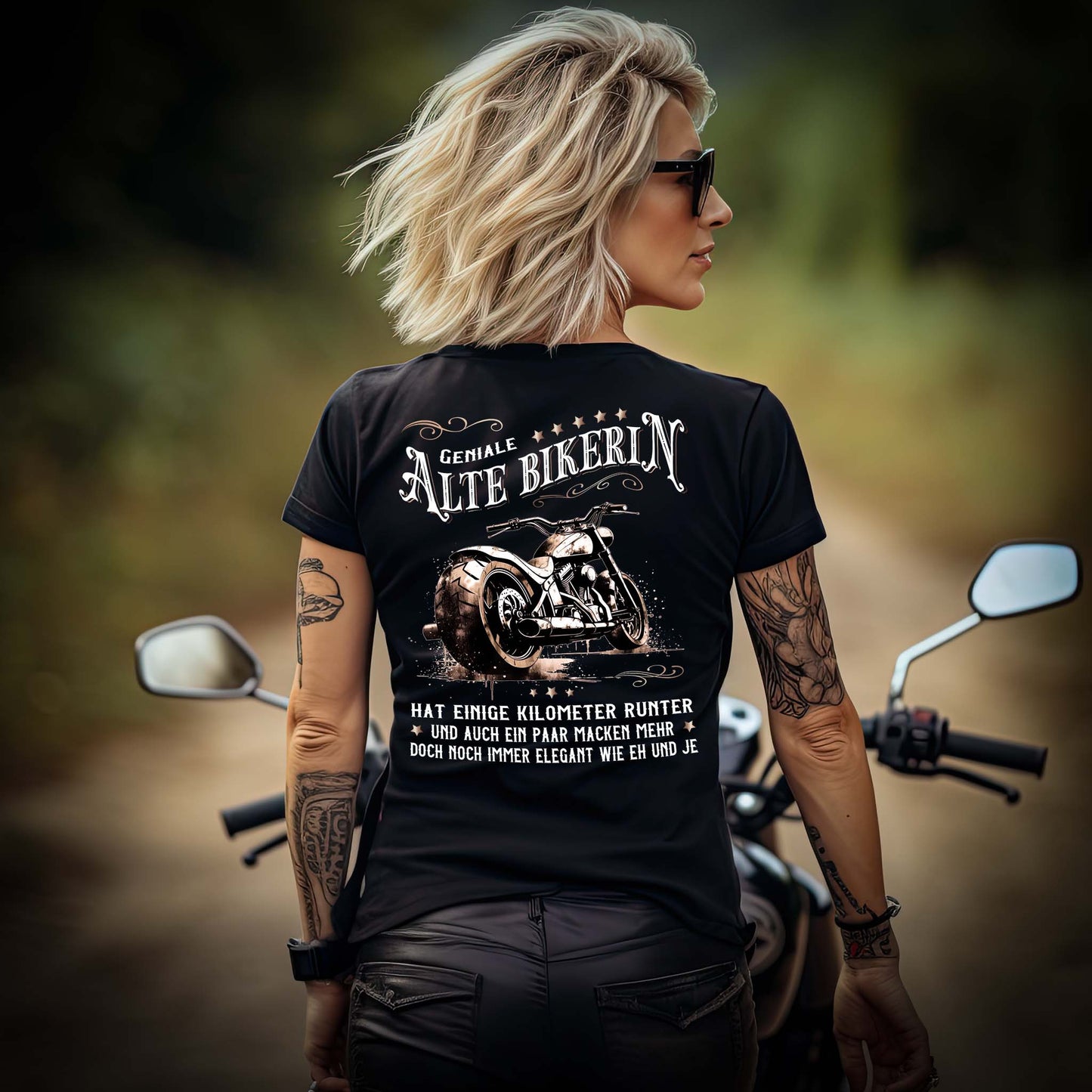 Eine Bikerin mit einem T-Shirt für Motorradfahrerinnen von Wingbikers mit dem Aufdruck, Alte Bikerin - Einige Kilometer Runter - Doch elegant wie eh und je - mit Back Print, in schwarz.