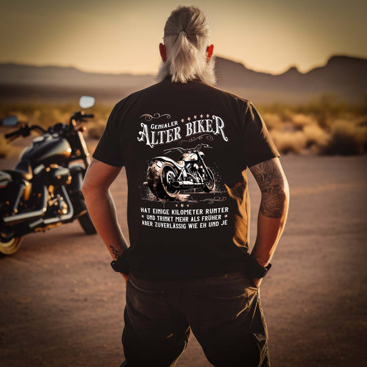Ein Biker mit einem T-Shirt für Motorradfahrer von Wingbikers mit dem Aufdruck, Alter Biker - Einige Kilometer runter, trinkt mehr - aber zuverlässig wie eh und je - mit Back Print, in schwarz.