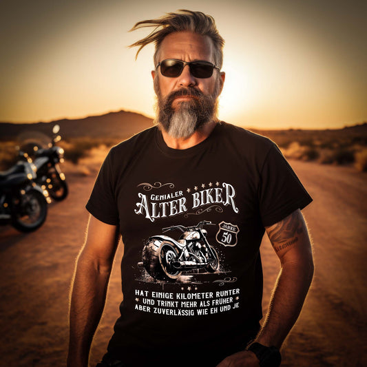Ein Biker mit einem Geburtstags- T-Shirt für Motorradfahrer von Wingbikers mit dem Aufdruck, Alter Biker - 50 Jahre - Einige Kilometer runter, trinkt mehr - aber zuverlässig wie eh und je - in schwarz.