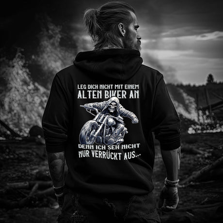 Ein Biker mit einem Hoodie für Motorradfahrer von Wingbikers mit dem Aufdruck, Leg dich nicht mit einem alten Biker an, denn ich seh nicht nur verrückt aus, als Back Print - in schwarz.