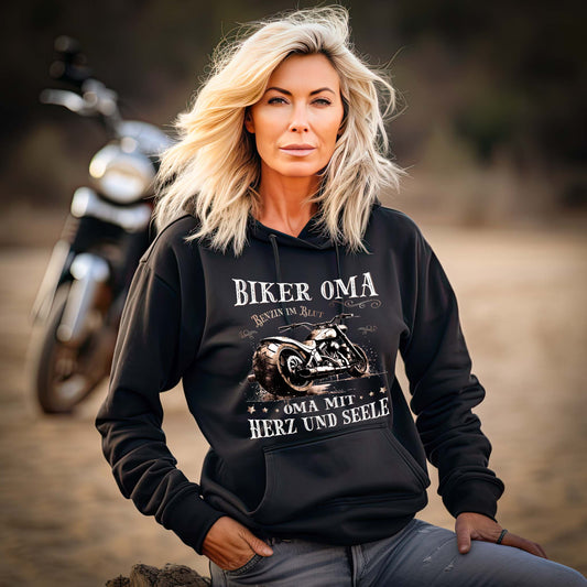 Eine Frau mit einem Damen Hoodie für Motorradfahrerinnen von Wingbikers mit dem Aufdruck, Biker Oma - Benzin im Blut - Oma mit Herz und Seele, in schwarz.