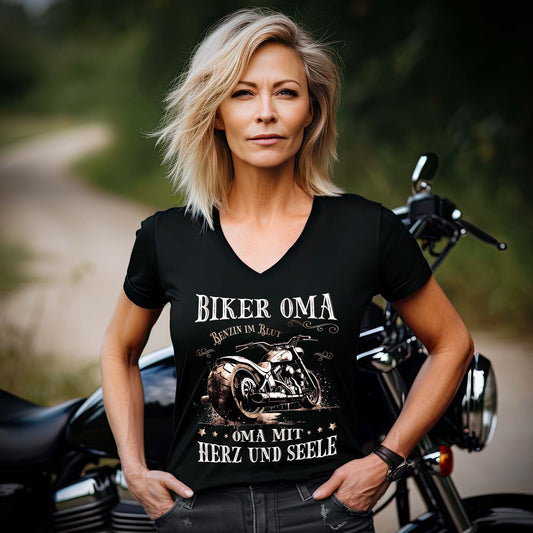 Eine Frau mit einem T-Shirt mit V-Ausschnitt für Motorradfahrerinnen von Wingbikers mit dem Aufdruck, Biker Oma - Benzin im Blut - Oma mit Herz und Seele, in schwarz.