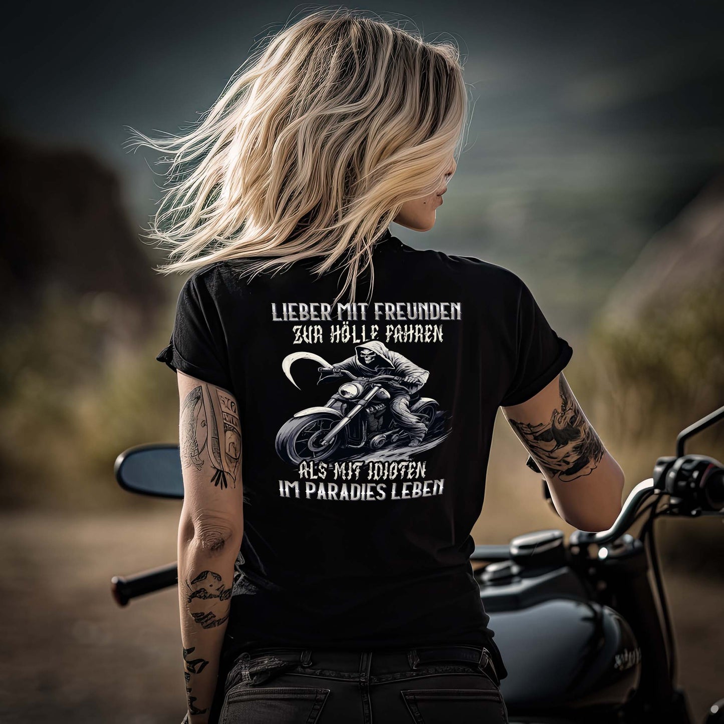 Eine Motorradfahrerin mit einem T-Shirt mit V-Ausschnitt von Wingbikers mit dem Aufdruck, Lieber mit Freunden zur Hölle fahren, als mit Idioten im Paradies leben, als Back Print, in schwarz.
