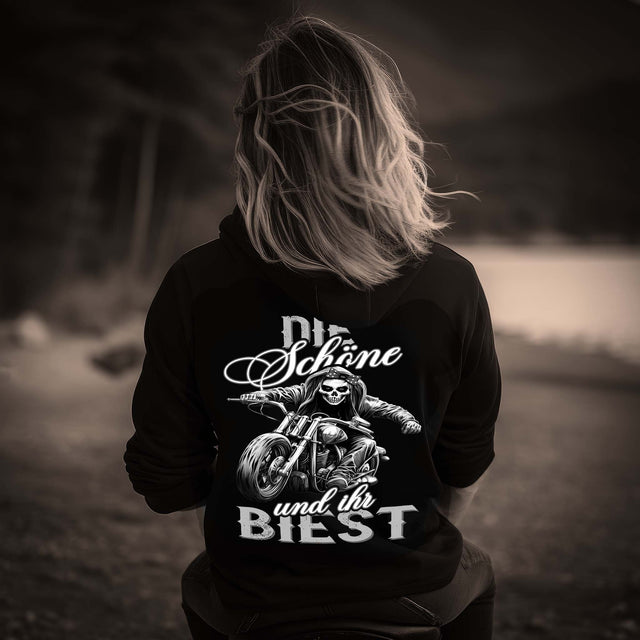 Eine Bikerin mit einem Hoodie für Motorradfahrerinnen von Wingbikers mit dem Aufdruck, Die Schöne und ihr Biest - mit Back Print, in schwarz.