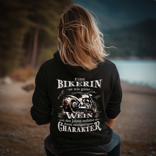 Eine Bikerin mit einer Reißverschluss-Jacke für Motorradfahrerinnen von Wingbikers mit dem Aufdruck, Eine Bikerin ist wie guter Wein - mit den Jahren entfaltet sie ihren einzigartigen Charakter - in schwarz.