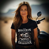 Eine Bikerin mit einem T-Shirt für Motorradfahrerinnen von Wingbikers mit dem Aufdruck, Eine Bikerin ist wie guter Wein - mit den Jahren entfaltet sie ihren einzigartigen Charakter - in schwarz.