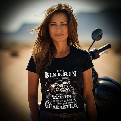 Eine Bikerin mit einem T-Shirt für Motorradfahrerinnen von Wingbikers mit dem Aufdruck, Eine Bikerin ist wie guter Wein - mit den Jahren entfaltet sie ihren einzigartigen Charakter - in schwarz.