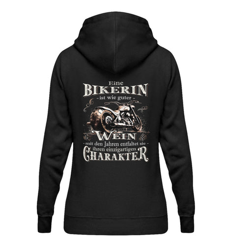 Ein Bikerin Hoodie für Motorradfahrerinnen von Wingbikers mit dem Aufdruck, Eine Bikerin ist wie guter Wein - mit den Jahren entfaltet sie ihren einzigartigen Charakter - mit Back Print, in schwarz.