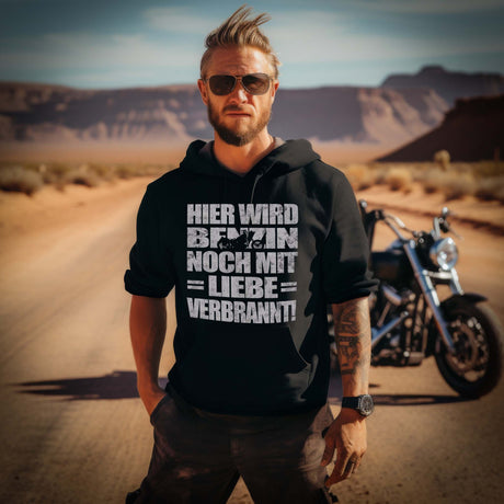 Ein Biker mit einem Hoodie für Motorradfahrer von Wingbikers mit dem Aufdruck, Hier wird Benzin noch mit Liebe verbrannt - in schwarz.