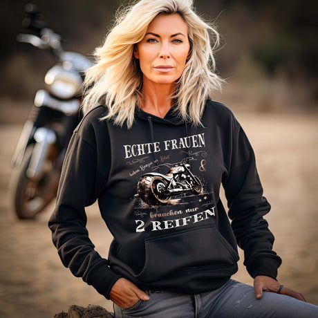 Eine Motorradfahrerin mit einem Damen Hoodie von Wingbikers mit dem Aufdruck, Echte Frauen brauchen nur zwei Reifen, in schwarz.