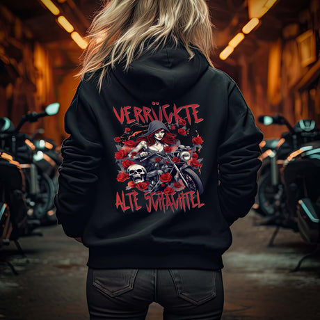 Eine Motorradfahrerin mit einer Reißverschluss-Jacke von Wingbikers mit dem Aufdruck, Verrückte alte Schachtel, als Back Print, in schwarz.