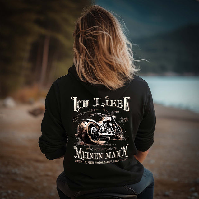 Eine Motorradfahrerin mit einer Reißverschluss-Jacke von Wingbikers mit dem Aufdruck, Ich liebe meinen Mann, wenn er mich Motorrad fahren lässt! - als Backprint in schwarz.