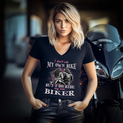 Eine Motorradfahrerin mit einem T-Shirt mit V-Ausschnitt von Wingbikers mit dem Aufdruck, I Don't Ride My Own Bike, But I Do Ride My Own Biker, in schwarz.