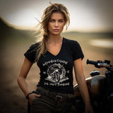 Eine Motorradfahrerin mit einem T-Shirt mit V-Ausschnitt von Wingbikers mit dem Aufdruck, Adventure Is Out There, in schwarz.