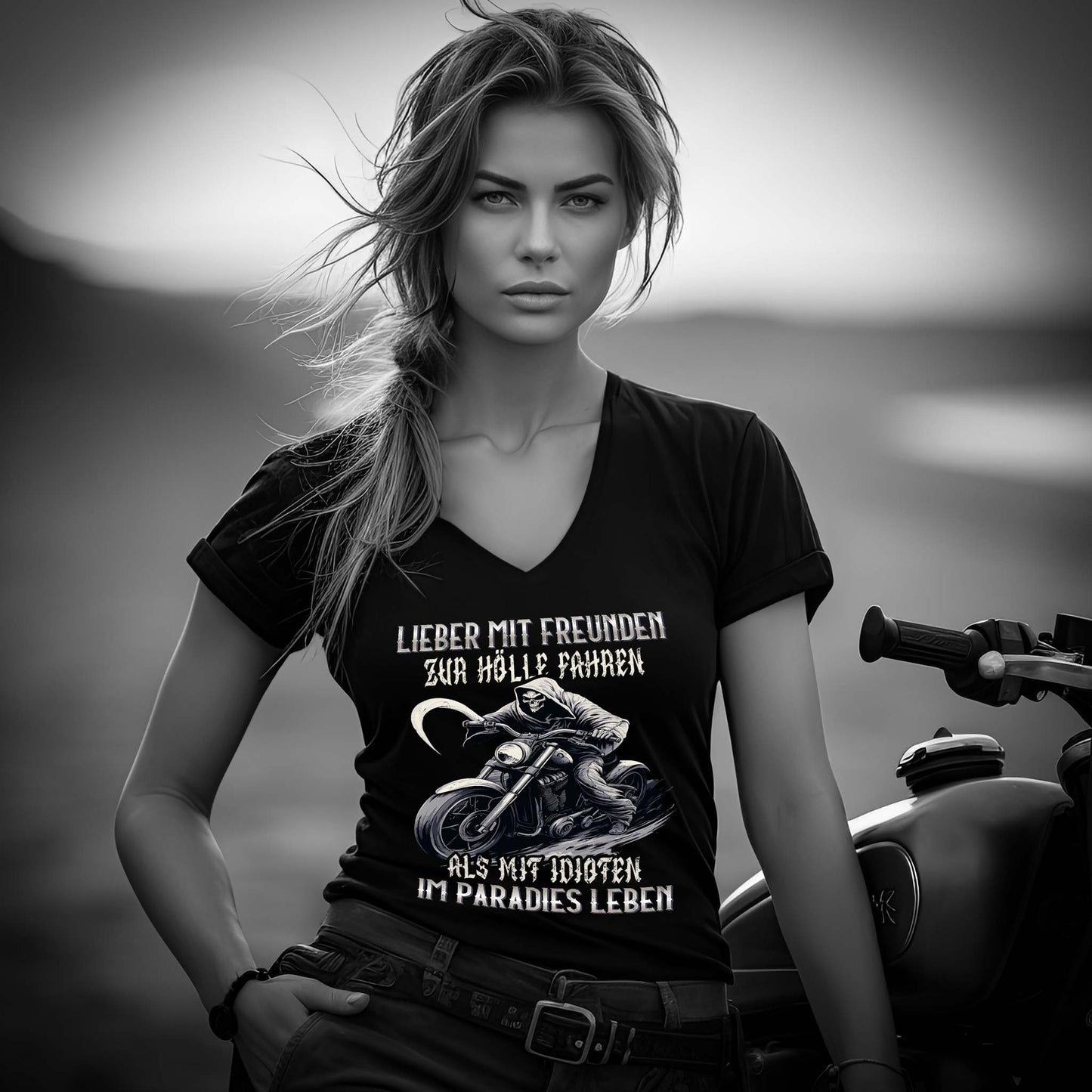 Eine Motorradfahrerin mit einem T-Shirt mit V-Ausschnitt von Wingbikers mit dem Aufdruck, Lieber mit Freunden zur Hölle fahren, als mit Idioten im Paradies leben, in schwarz.