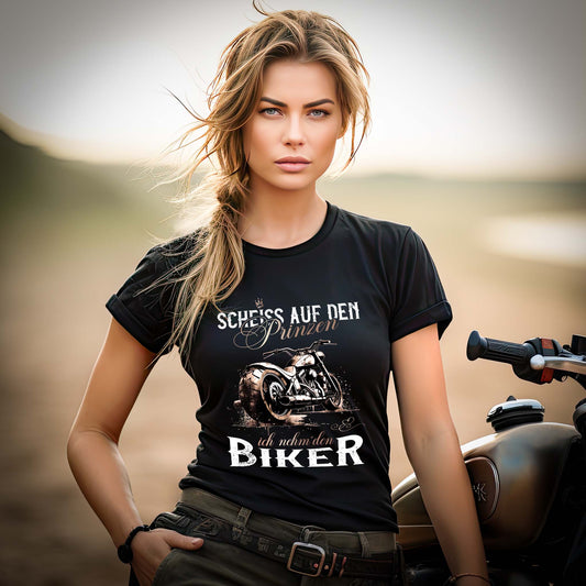 Eine Bikerin mit einem T-Shirt für Motorradfahrerinnen, von Wingbikers, mit dem Aufdruck, Scheiß auf den Prinzen, ich nehm' den Biker - im vintage Stil, in schwarz, leger geschnitten.