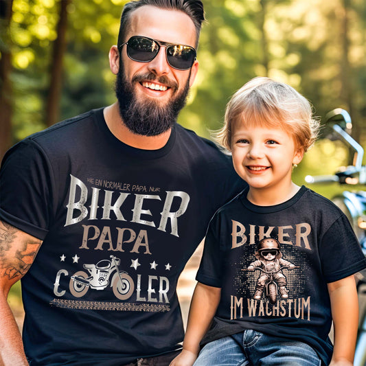 Ein  Papa mit einem T-Shirt für motorradfahrende Väter von Wingbikers mit dem Aufdruck, Biker Papa, wie ein normaler Papa, nur viel cooler, in schwarz.