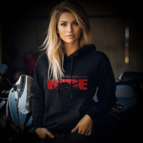 Eine Motorradfahrerin mit einem Hoodie von Wingbikers mit dem roten Schriftzug, Life Is Better When You Ride - mit einem Motorrad, in schwarz.