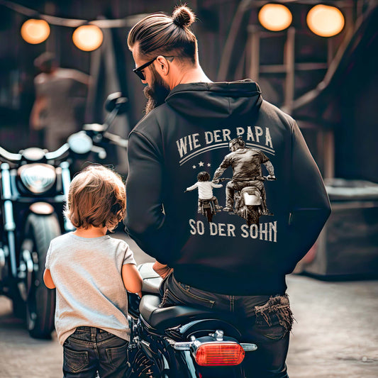 Ein Papa mit einem Hoodie für Motorradfahrende Väter von Wingbikers mit dem Aufdruck, Wie der Papa, so der Sohn, in schwarz.