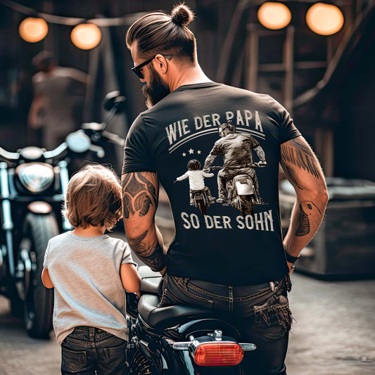 Ein Vater mit einem T-Shirt für Motorradfahrende Väter von Wingbikers mit dem Aufdruck, Wie der Papa, so der Sohn, als Back Print - in schwarz.