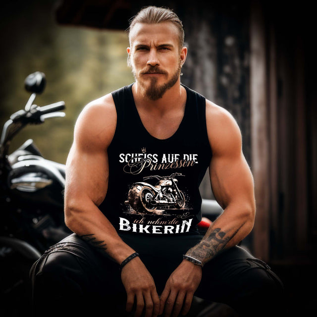 Ein Biker mit einem Tanktop für Motorradfahrer von Wingbikers mit dem Aufdruck, Scheiß auf die Prinzessin - Ich nehm´ die Bikerin - in schwarz.