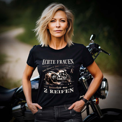 Eine Motorradfahrerin mit einem T-Shirt von Wingbikers mit dem Aufdruck, Echte Frauen brauchen nur zwei Reifen, in schwarz.