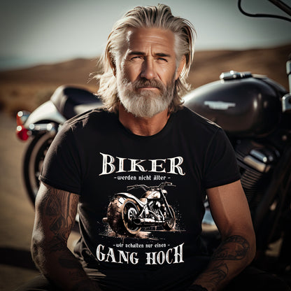 Ein Biker mit einem T-Shirt für Motorradfahrer von Wingbikers mit dem Aufdruck, Biker werden nicht älter - Wir schalten nur einen Gang hoch! - in schwarz.