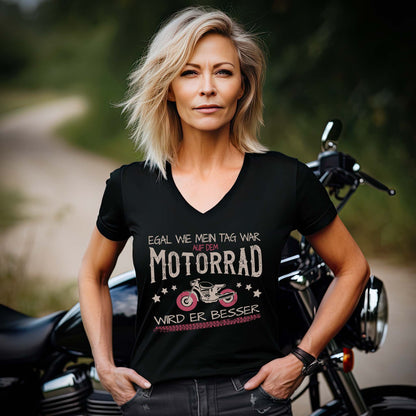 Eine Frau mit einem T-Shirt mit V-Ausschnitt für Motorradfahrerinnen von Wingbikers mit dem Aufdruck, Egal wie mein Tag war, auf dem Motorrad wird er besser, in schwarz.