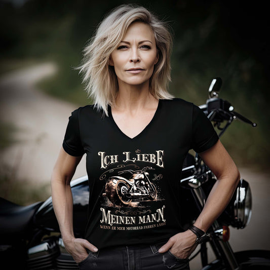 Eine Motorradfahrerin mit einem T-Shirt mit V-Ausschnitt von Wingbikers mit dem Aufdruck, Ich liebe meinen Mann, wenn er mich Motorrad fahren lässt! - in schwarz.