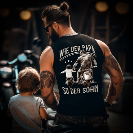 Ein Motorradfahrender Papa mit einem Tanktop für Väter von Wingbikers mit dem Aufdruck, Wie der Papa, so der Sohn, als Back Print - in schwarz.