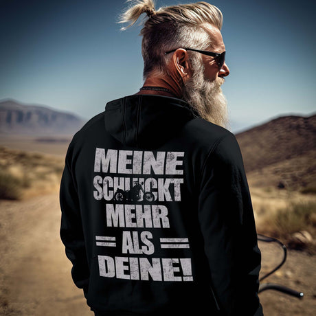 Ein Biker mit einem Hoodie für Motorradfahrer von Wingbikers mit dem Aufdruck, Meine schluckt mehr als deine! mit einem Motorrad, als Back Print, in schwarz.