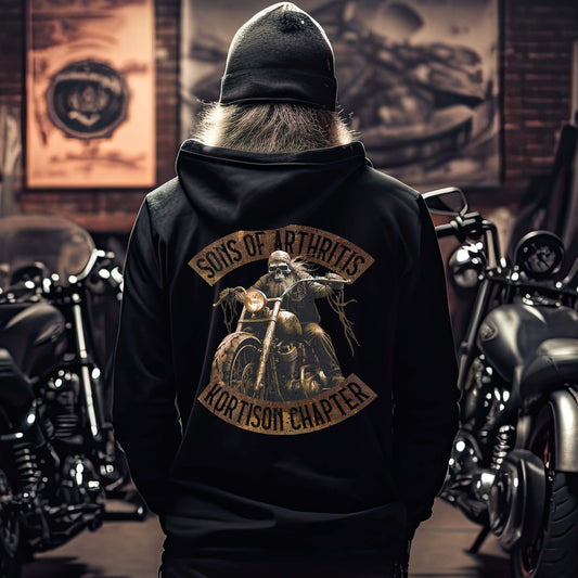 Ein Biker mit einer Reißverschluss-Jacke für Motorradfahrer von Wingbikers mit dem Aufdruck, Sons of Arthritis - Kortison Chapter, in schwarz.