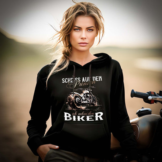 Eine Motorradfahrerin mit einem Hoodie von Wingbikers mit dem Aufdruck, Scheiß auf den Prinzen, ich nehm' den Biker, in schwarz.