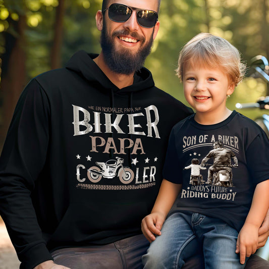 Ein Papa mit einem Hoodie für motorradfahrende Väter von Wingbikers mit dem Aufdruck, Biker Papa, wie ein normaler Papa, nur viel cooler, in schwarz.