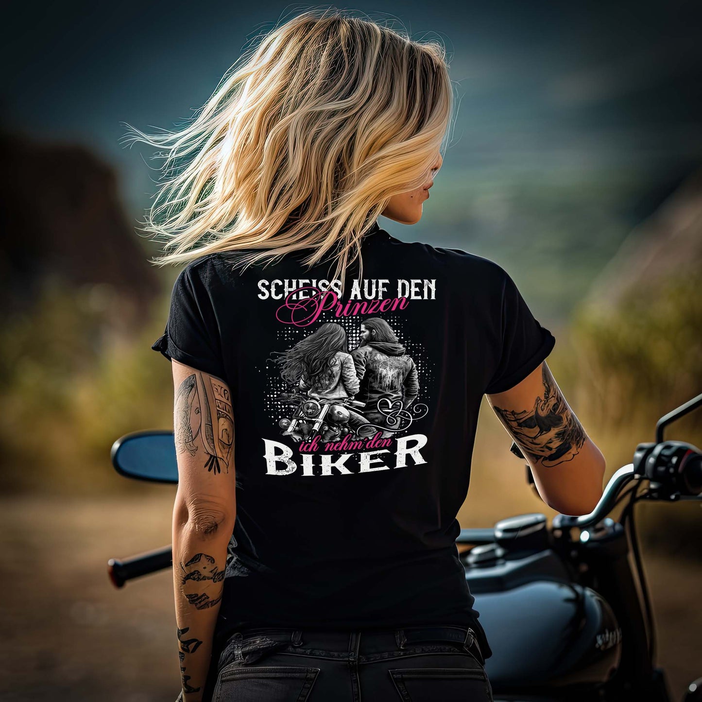 Ein Motorradfahrerin mit einem T-Shirt mit V-Ausschnitt von Wingbikers mit dem Aufdruck, Scheiß auf den Prinzen, ich nehm' den Biker, als Backprint in schwarz.
