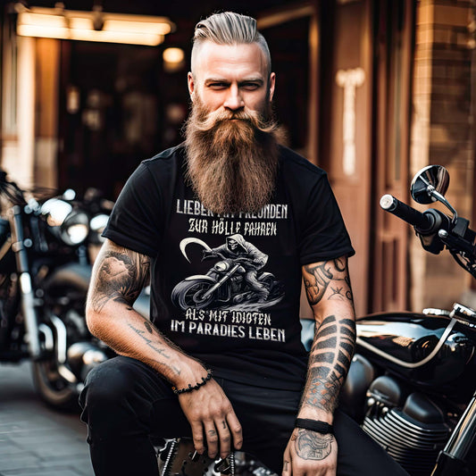 Ein Motorradfahrer mit einem Biker T-Shirt mit dem Aufdruck, Lieber mit Freunden zur Hölle fahren, als mit Idioten im Paradies leben in schwarz. 