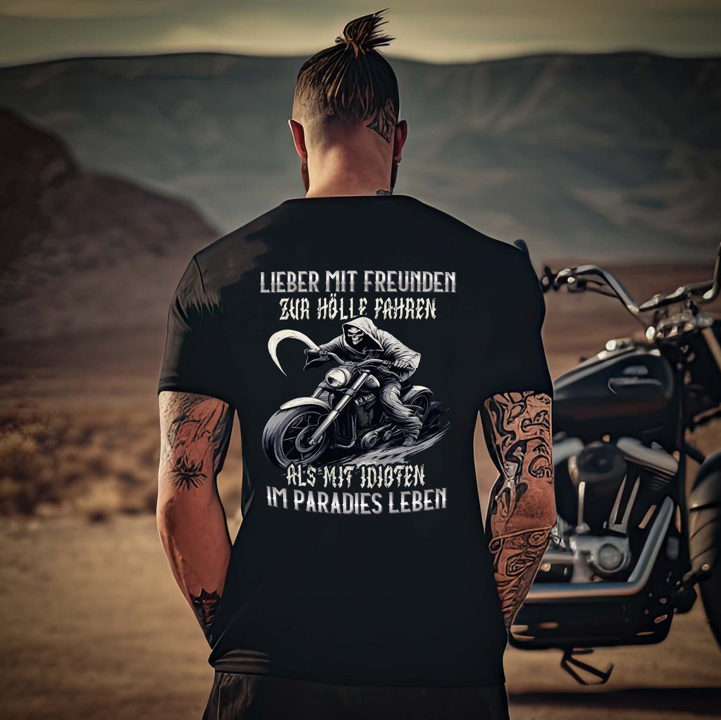 Ein Motorradfahrer vor seinem Motorrad mit einem Biker T-Shirt mit dem Aufdruck, Lieber mit Freunden zur Hölle fahren, als mit Idioten im Paradies leben, als Back Print in schwarz. 