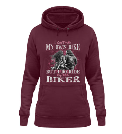 Ein Damen Hoodie für Motorradfahrerinnen von Wingbikers mit dem Aufdruck, I Don't Ride My Own Bike, But I Do Ride My Own Biker, in burgunder weinrot.