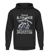 Ein Biker Hoodie für Motorradfahrer von Wingbikers mit dem Aufdruck, Achtung alter Biker - Gib ihm Öl und hilf ihm auf sein Motorrad - in schwarz.