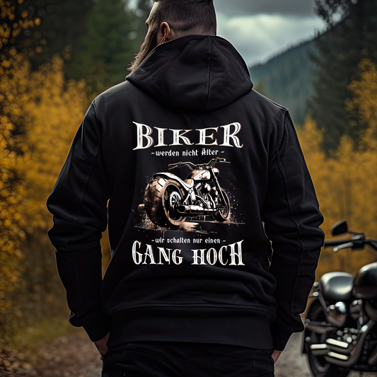 Ein Biker mit einem Hoodie für Motorradfahrer von Wingbikers mit dem Aufdruck, Biker werden nicht älter - Wir schalten nur einen Gang hoch! mit Back Print, in schwarz.